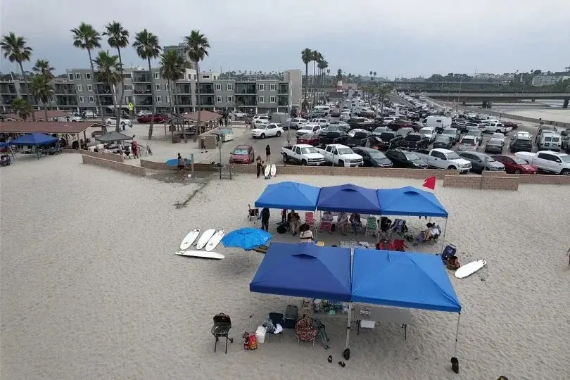 Aerial view of the Shred Dog Surf Camp on the beach in summer 2023, blue canopies set up on the sand